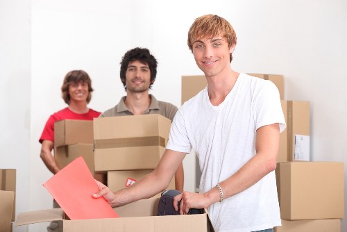 Local removals workers handling packed boxes inside a Greenwich flat